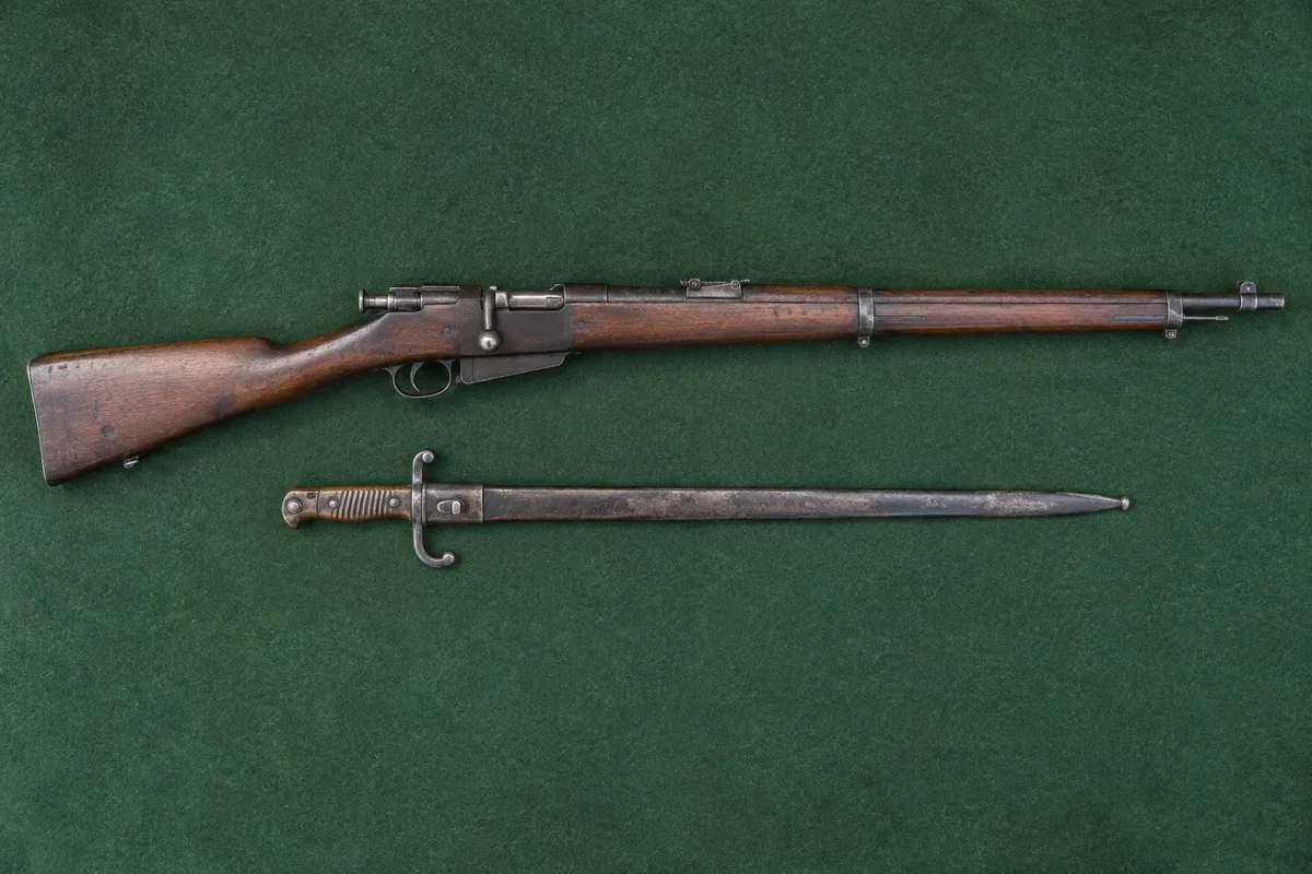 Fusil ancien à culasse mobile sur un feutre vert avec sa baïonnette