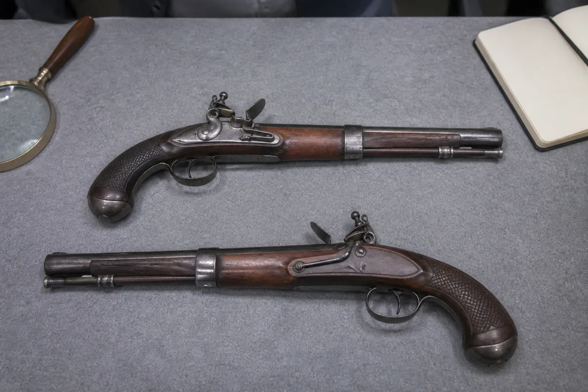 Coffret de pistolets ouvert sur une table d&rsquo;expertise, deux armes symétriques dans leurs logements