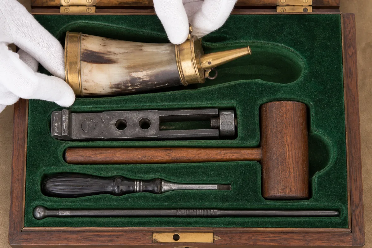 Accessoires d&rsquo;un coffret ancien alignés dans leurs logements de drap vert